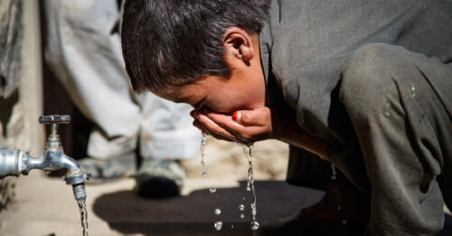 A young boy drinks clean water from a Medair-built water point in his village in Bamyan Province.  Medair builds water points in remote villages in the Central Highlands and provides hygiene training to help combat the spread of waterborne diseases.